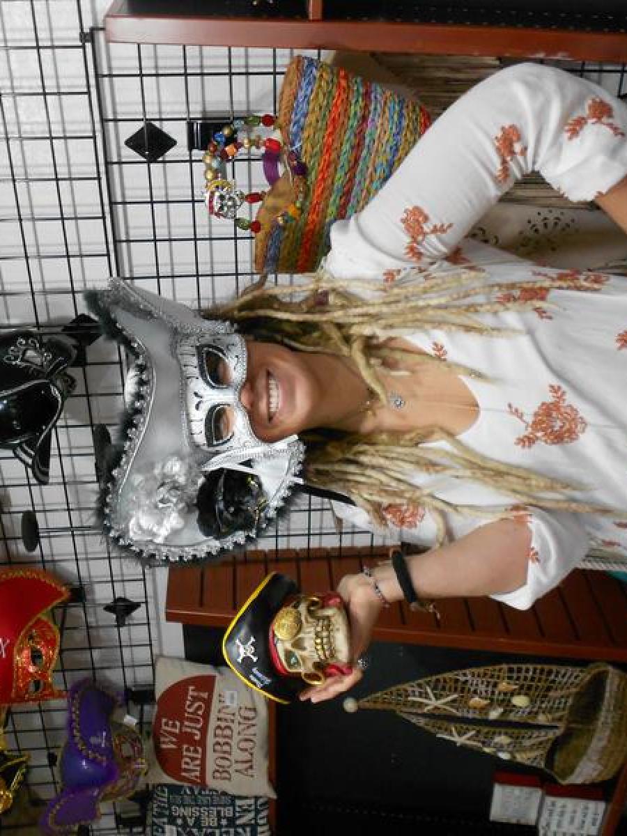 Women wearing mask with a hat and holding small skull model at the gift shop.