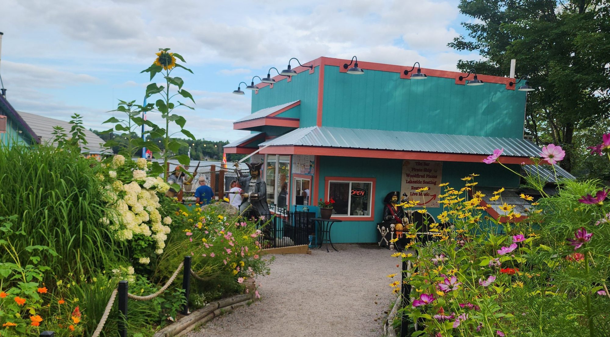 Vibrant garden path leading to a colorful building with a red and teal facade.